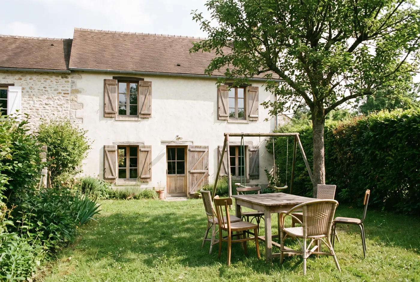 Jardin d’une maison de famille avec une table et des chaises dépareillées