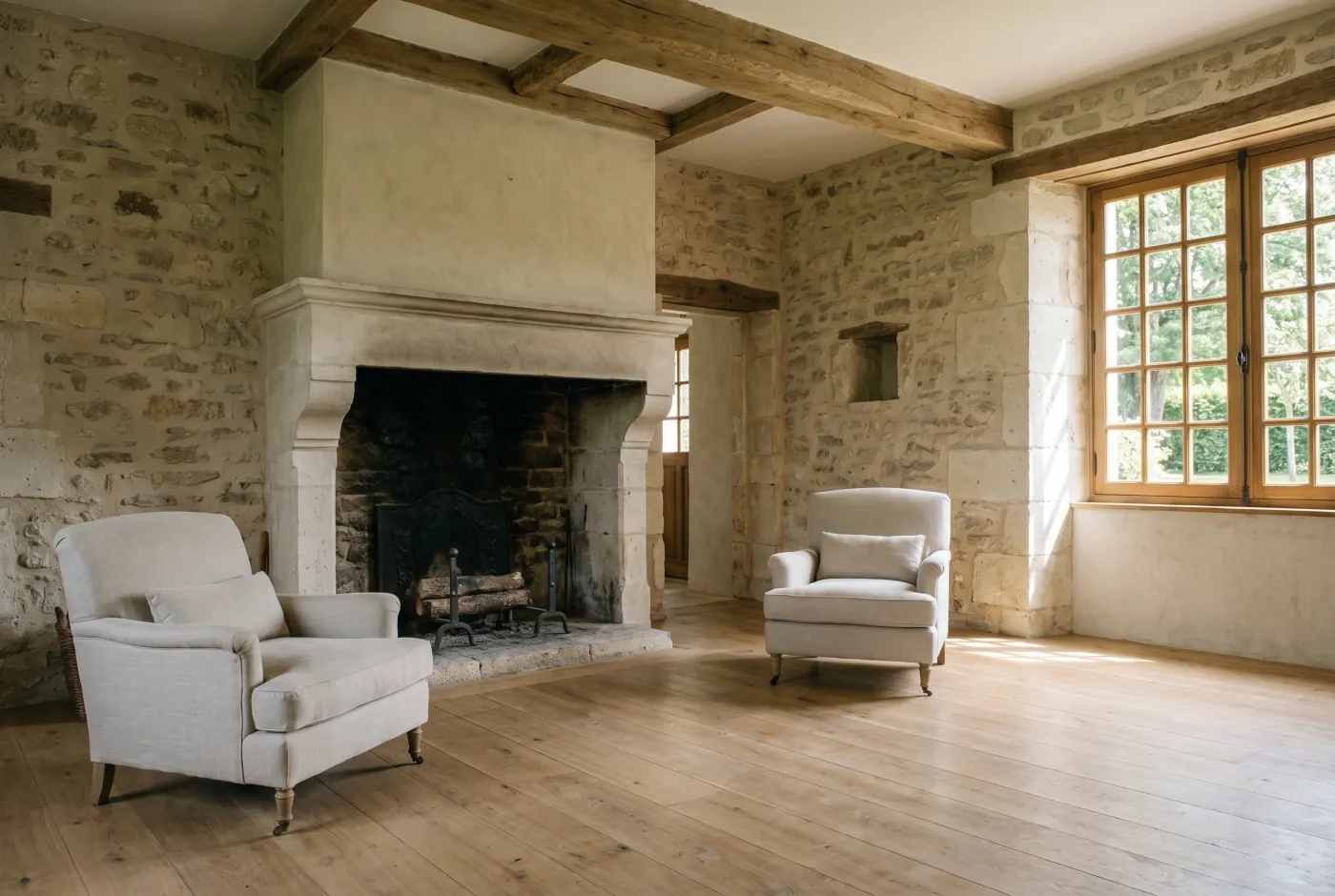 Séjour avec deux fauteuils séparés de part et d’autre d’une cheminée en pierre