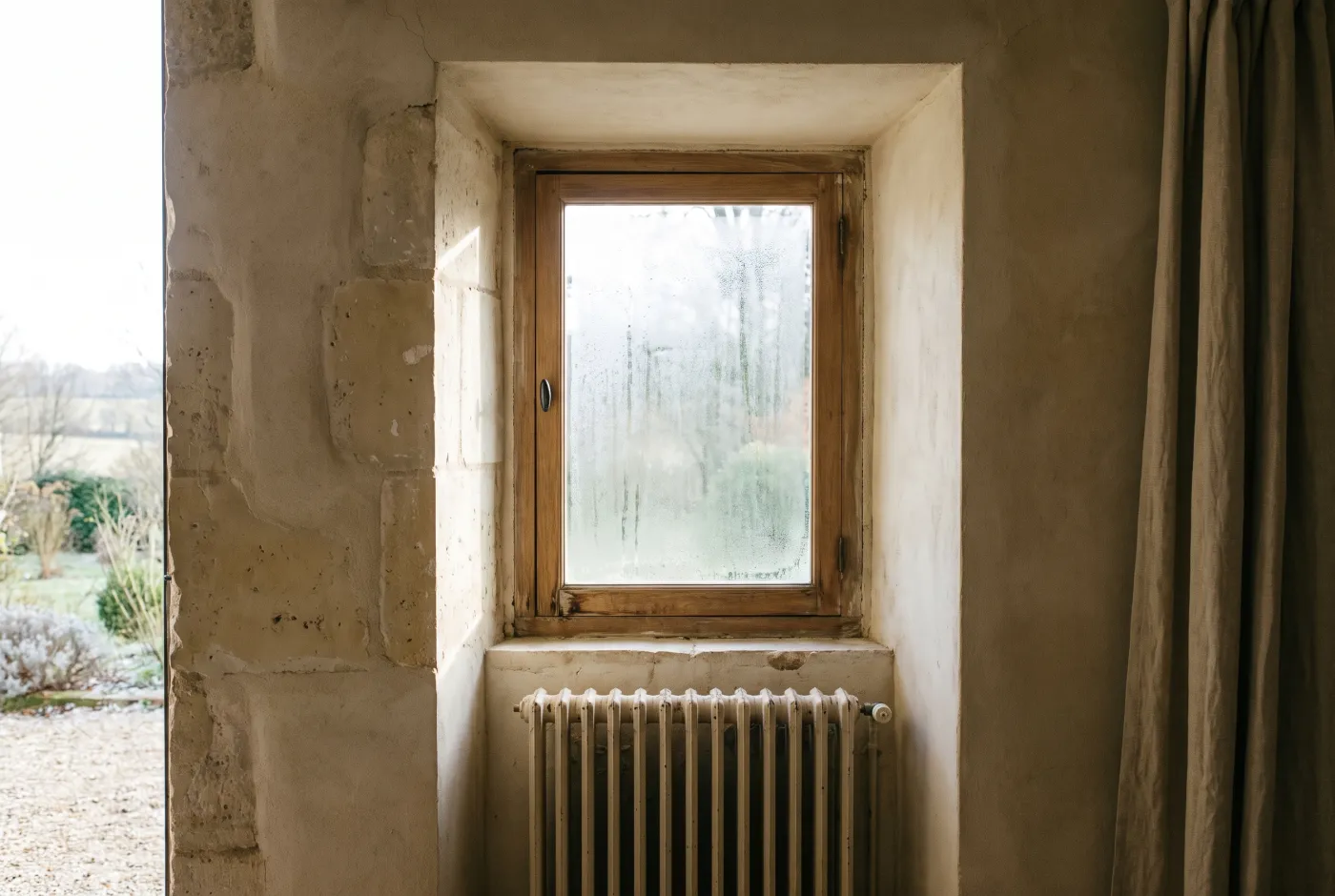 Fenêtre à simple vitrage et radiateur en fonte dans une maison ancienne