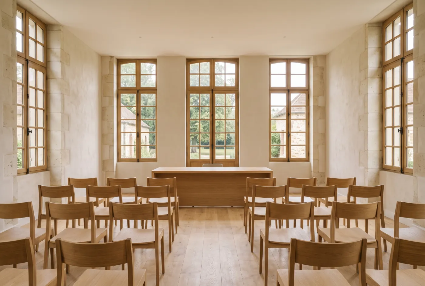Salle d’étude notariale, chaises alignées face à un bureau de bois clair